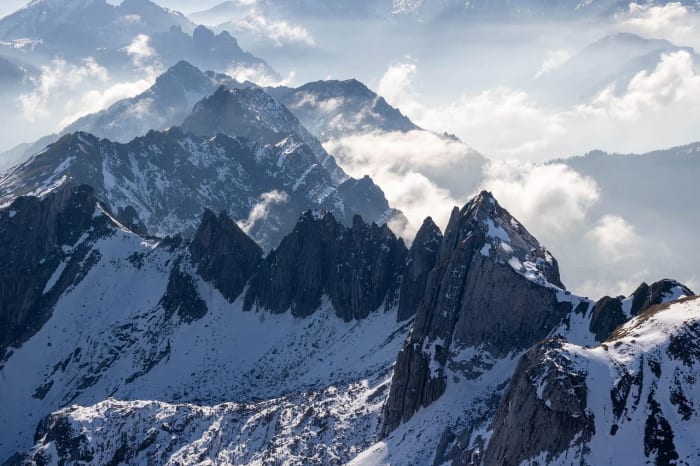 Montañas nevadas con nubes entre picos rocosos