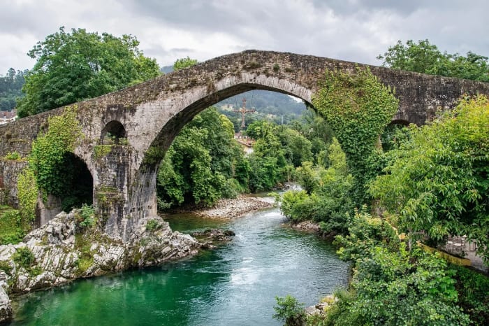 Puente medieval de piedra sobre un río verde