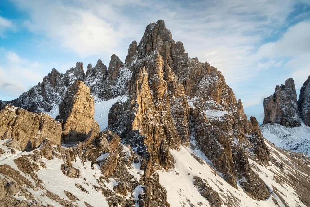 Crestas rocosas de una montaña con nieve bajo un cielo azul claro