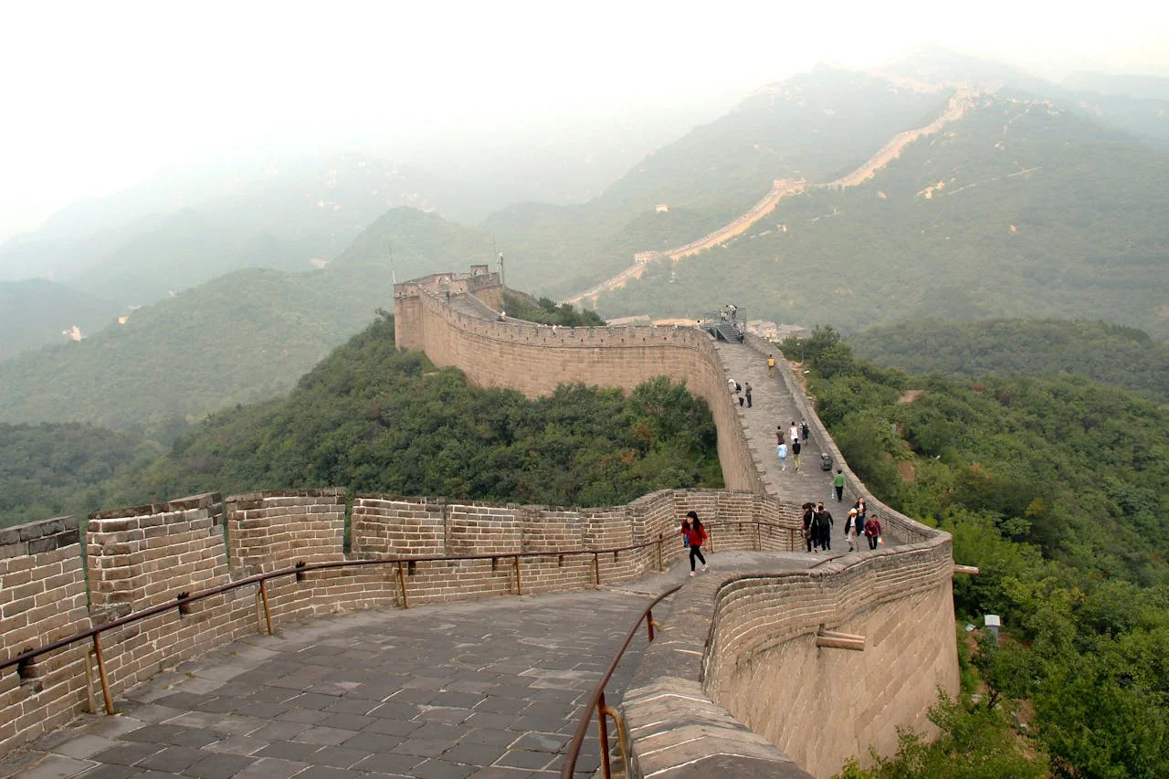 Vista de la Gran Muralla China en Mutianyu con sus fortificaciones y sendero pavimentado serpenteando a través de montañas arboladas