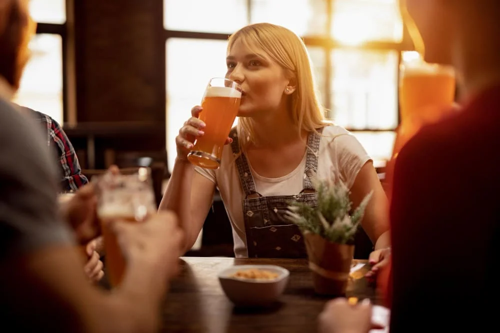 Imagen de una joven mujer gustando de una cerveza.