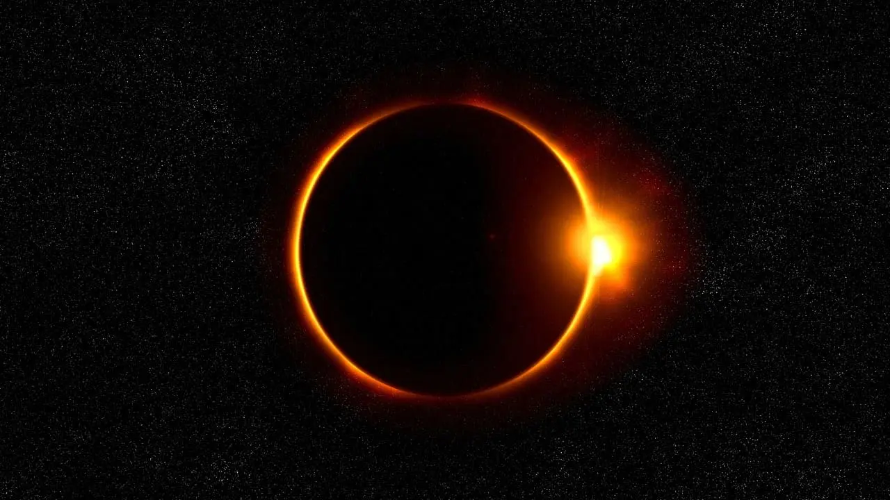 Eclipse solar con la Luna bloqueando parcialmente la luz del Sol, formando un anillo luminoso en un cielo estrellado.