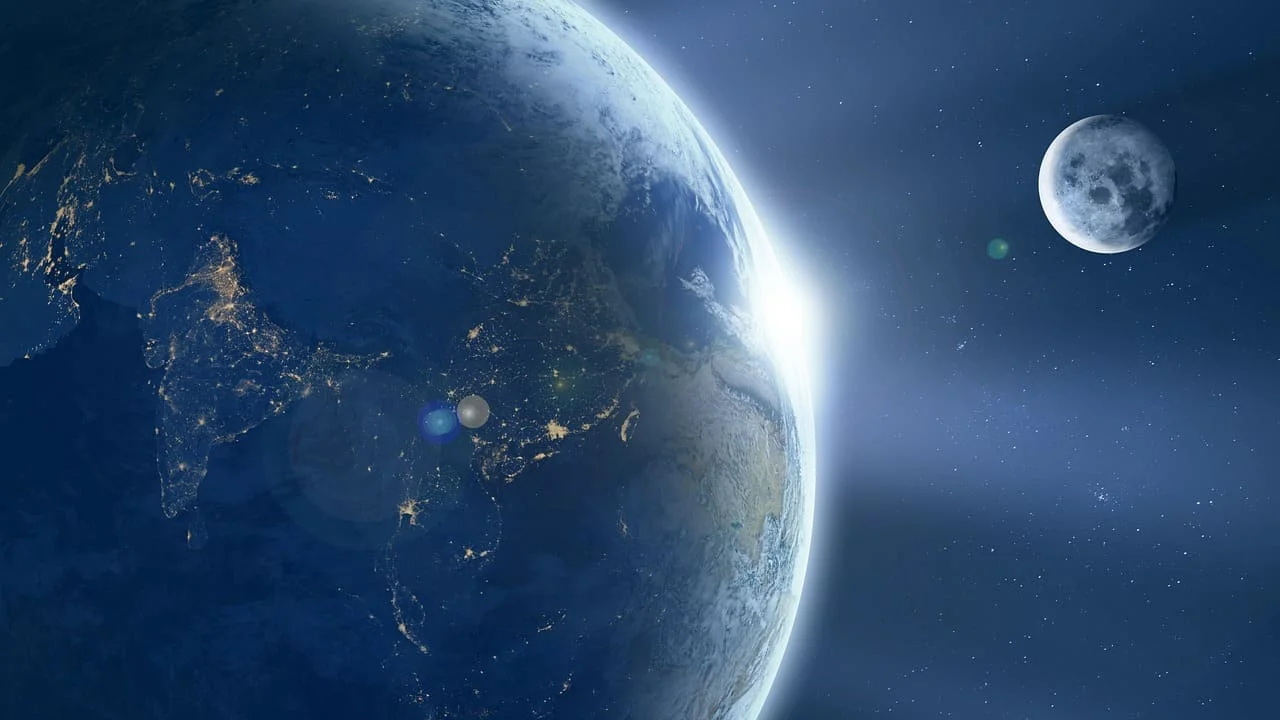 Vista del planeta Tierra desde el espacio con la Luna al fondo, mostrando continentes iluminados y un amanecer brillante.
