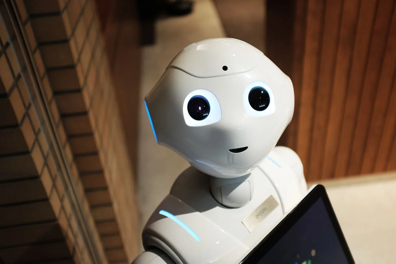 Robot humanoide blanco con ojos grandes y una pantalla táctil integrada en el pecho.