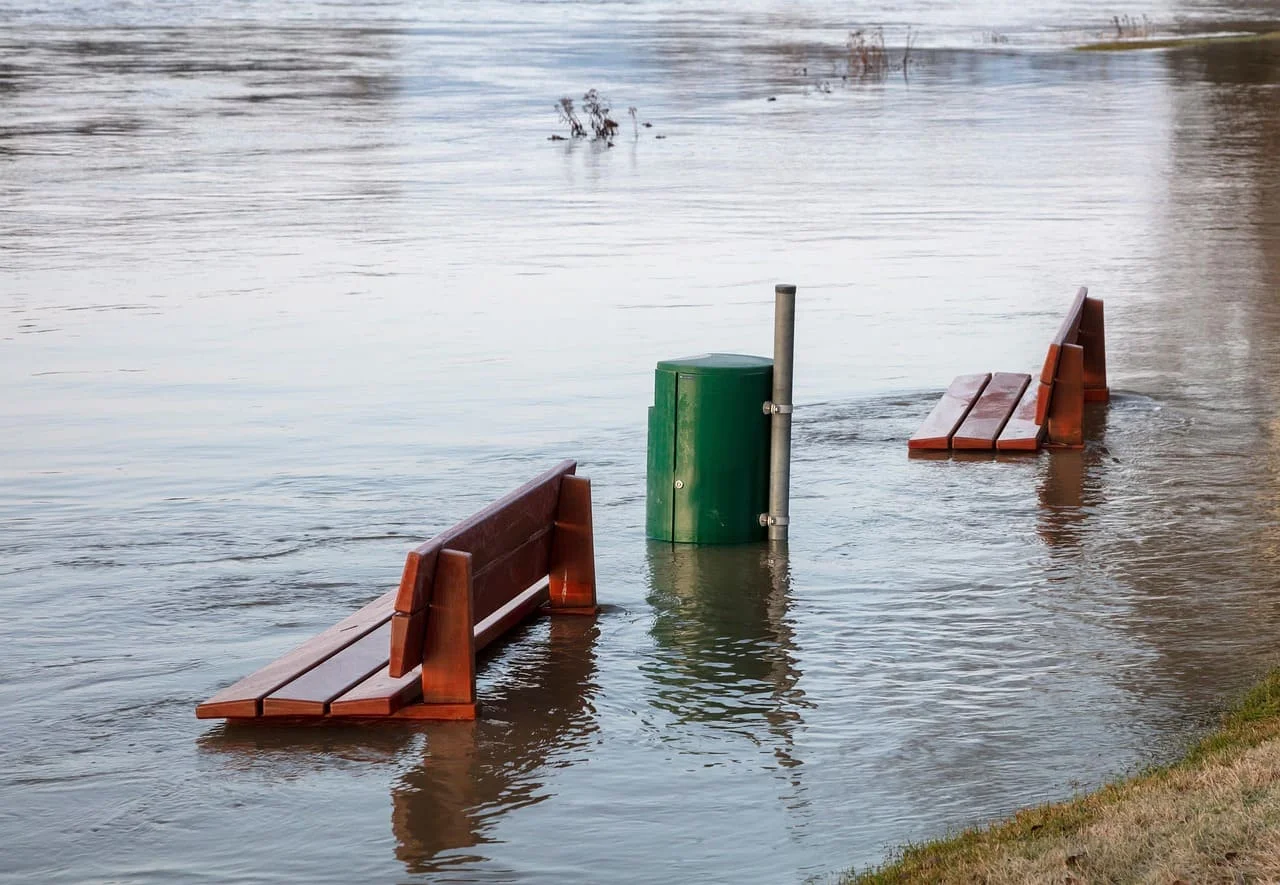 Bancas parcialmente sumergidas por una inundación en una zona urbana.