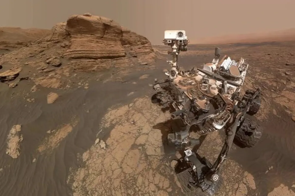 El rover Curiosity en Marte frente a una formación rocosa en capas, cerca de la colina Devil’s Gate en el cráter Gale