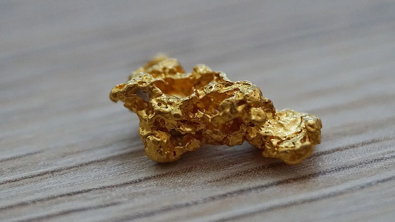 Pepita de oro sobre superficie de madera clara