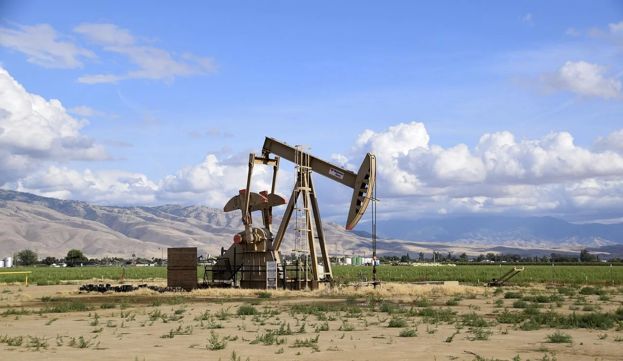 Pozo de extracción petrolera en un campo abierto con montañas al fondo
