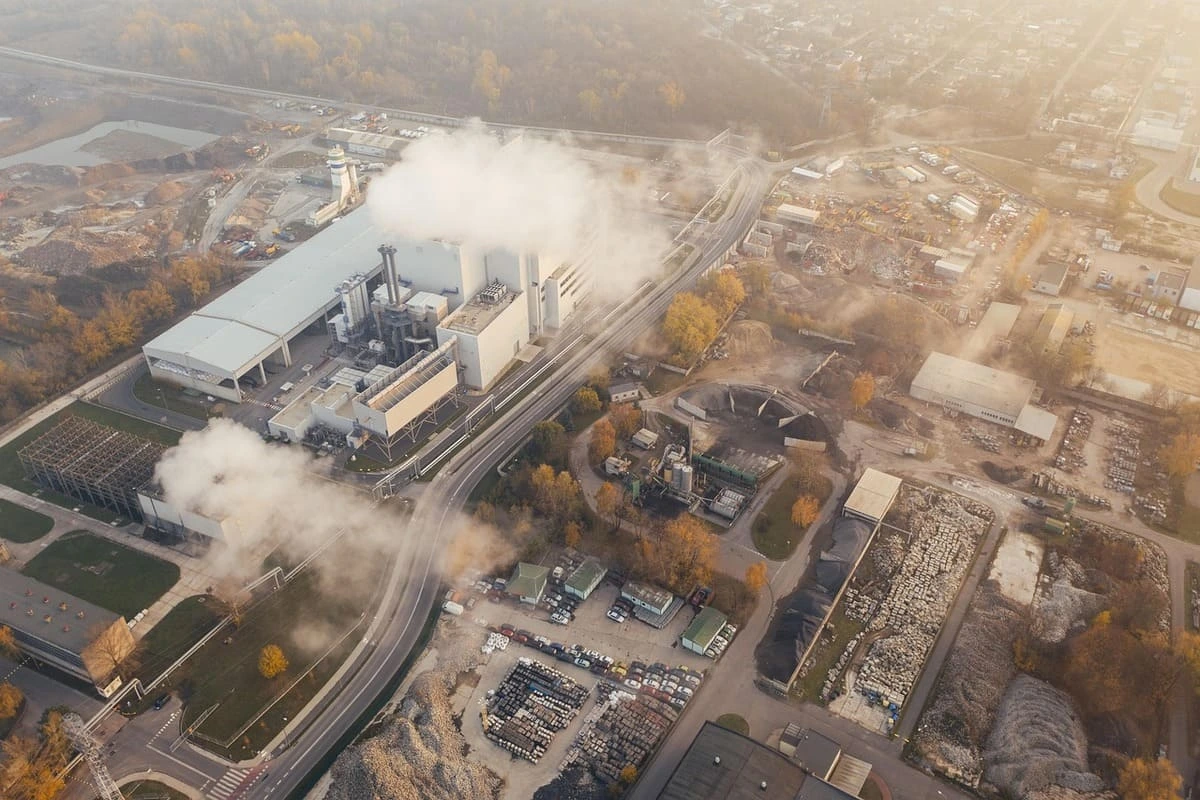 Vista aérea de una planta industrial emitiendo contaminantes en un área urbana
