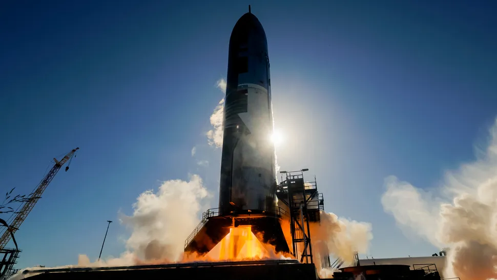 Cohete Starship en posición vertical sobre la plataforma de pruebas de SpaceX con fuego saliendo de la base