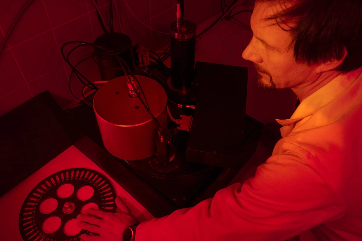 Investigador en laboratorio de datación óptica OSL con tubos y equipos especializados