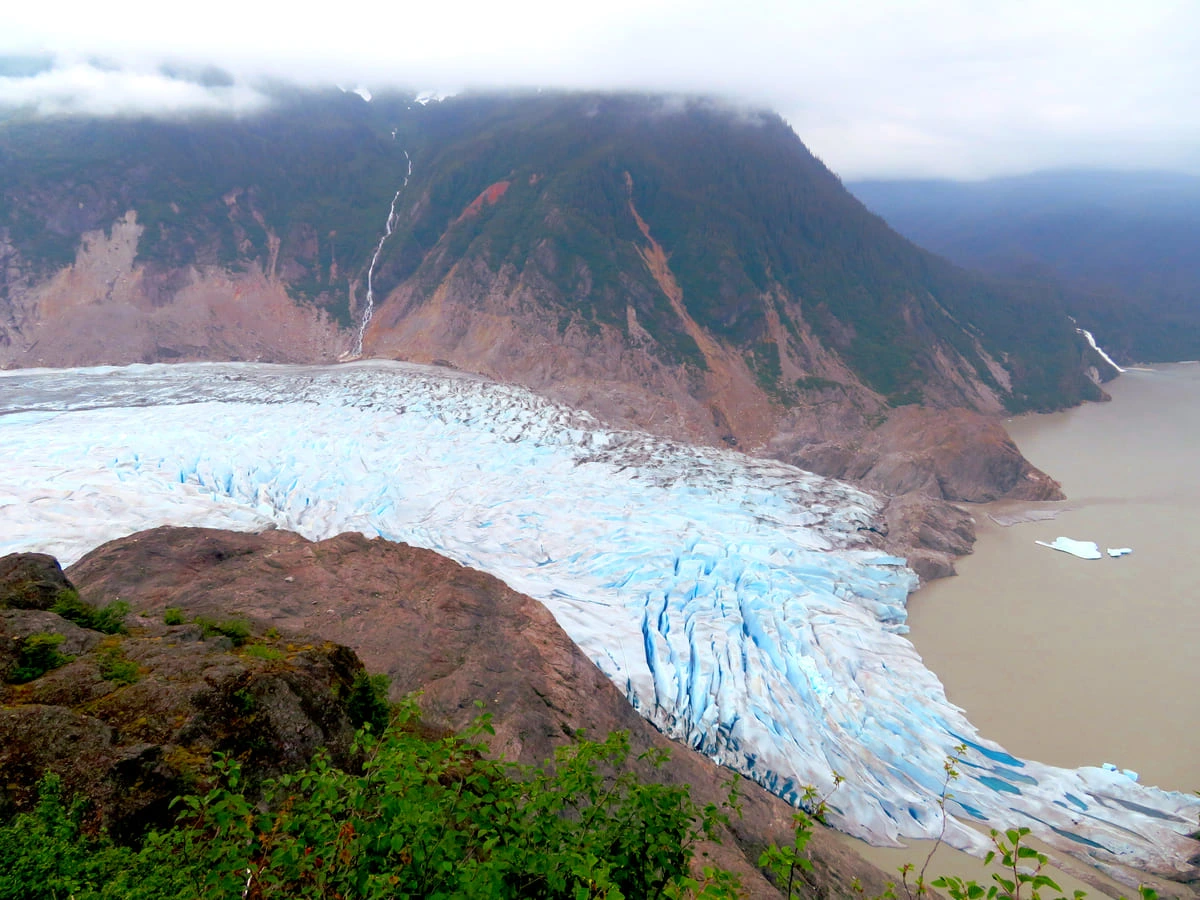 Glaciar moderno descendiendo entre montañas del sureste de Alaska bajo un cielo gris