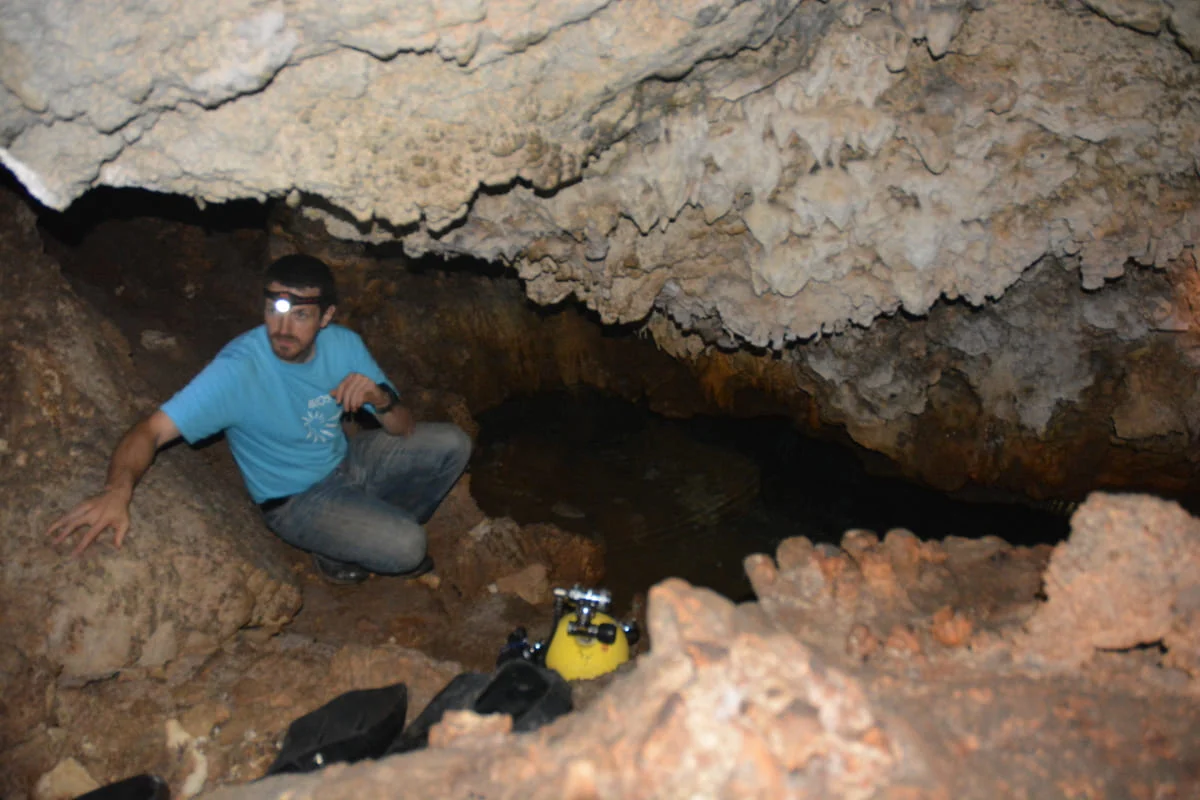 Científico explorando la entrada rocosa de la cueva Roadside durante una campaña de investigación