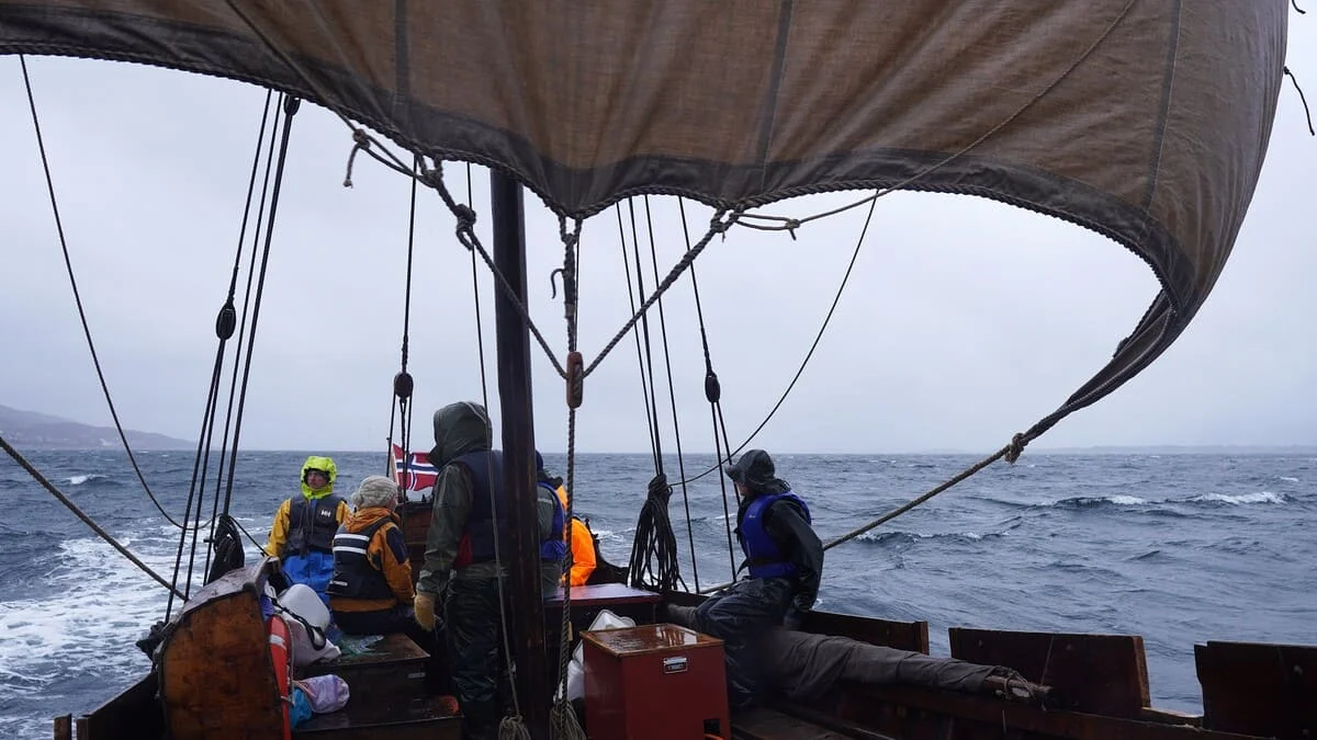 Barco tradicional navegando en mar abierto, bajo cielo parcialmente despejado