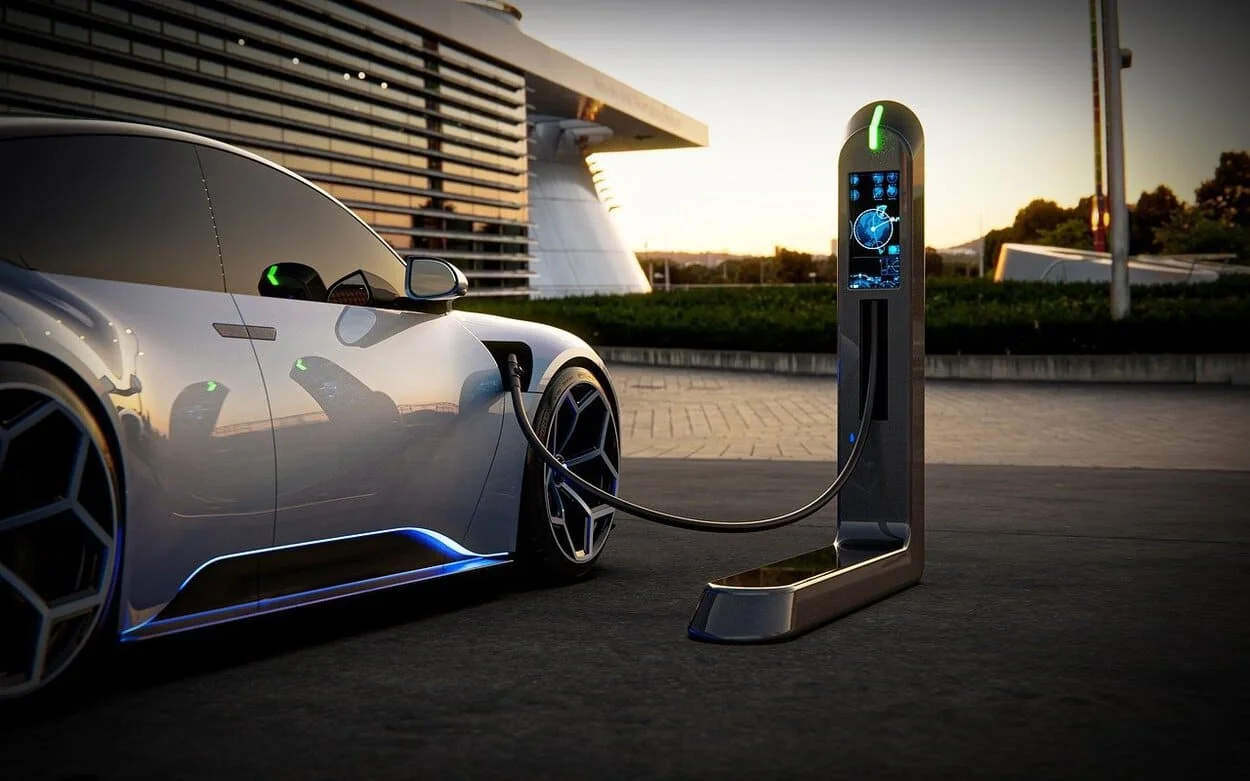 Coche eléctrico moderno conectado a una estación de carga urbana al atardecer
