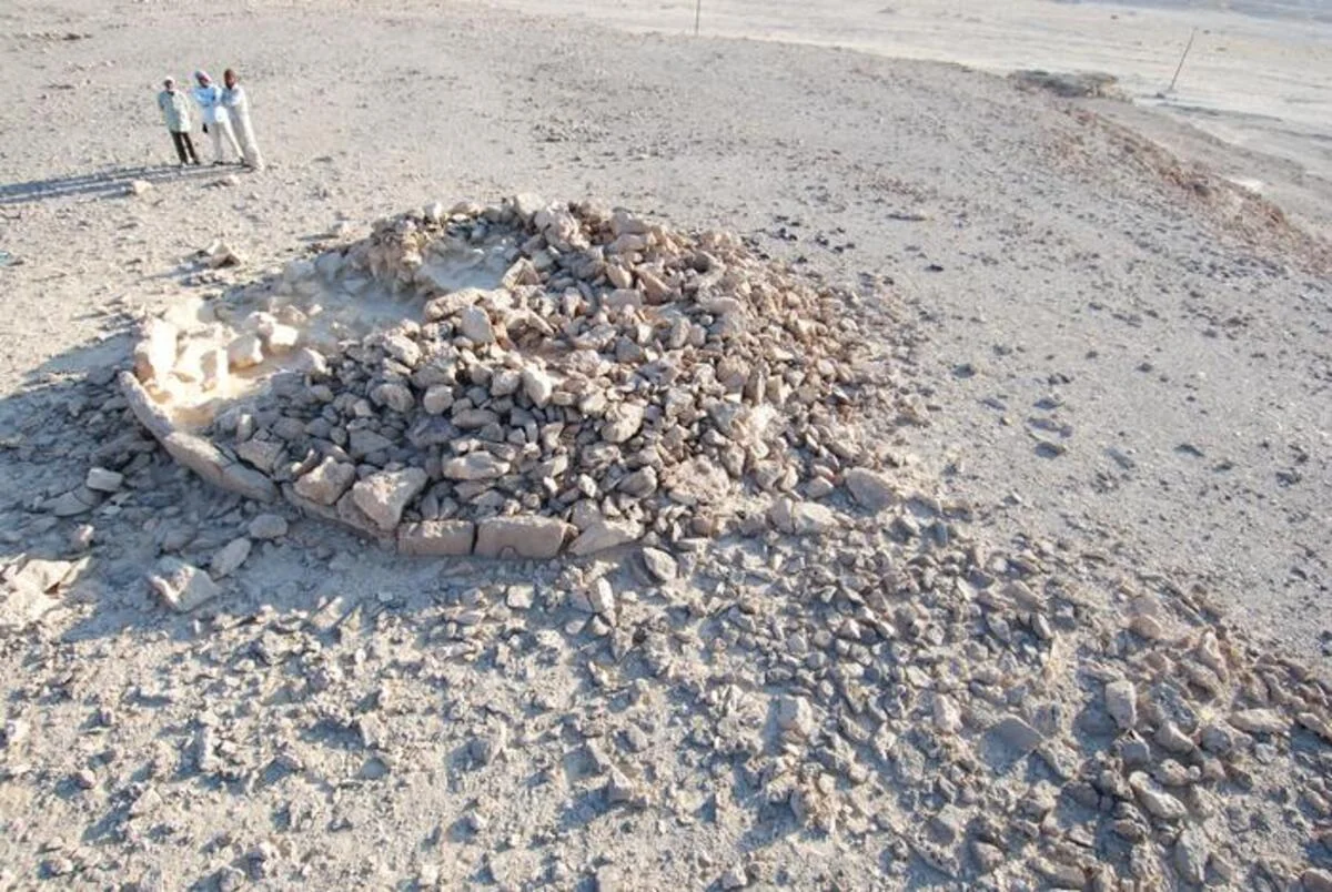 Investigadores examinando los restos de un monumento de plataforma