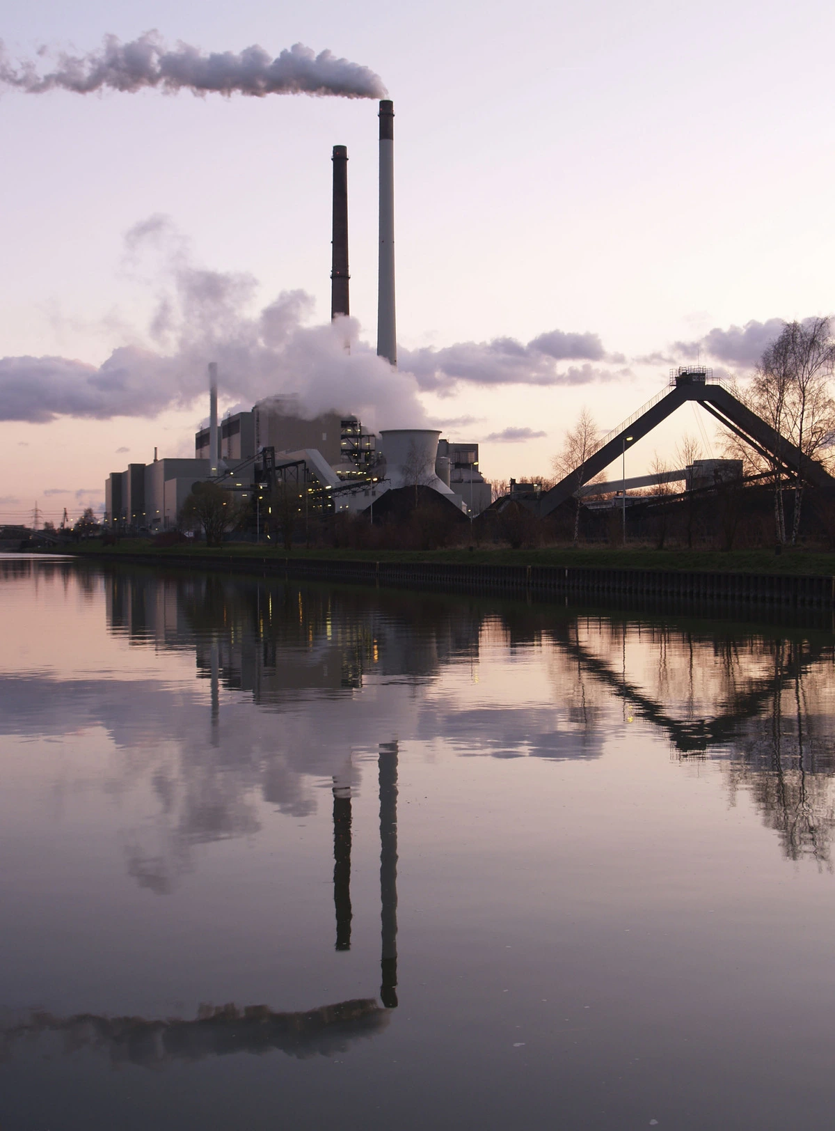 Chimeneas industriales de una central de carbón emitiendo vapor y gases al atardecer