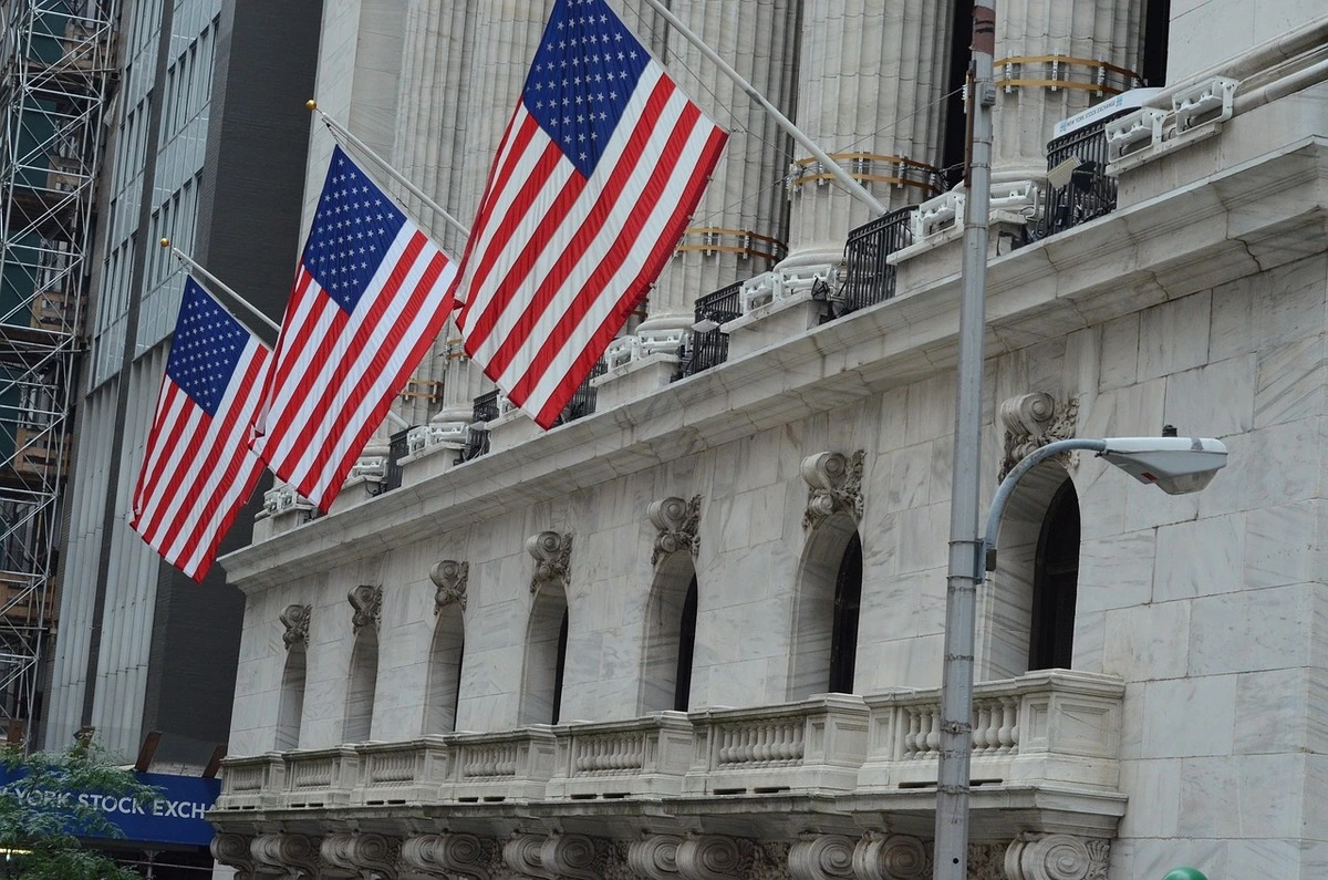 Fachada de la Bolsa de Nueva York con varias banderas de Estados Unidos ondeando.