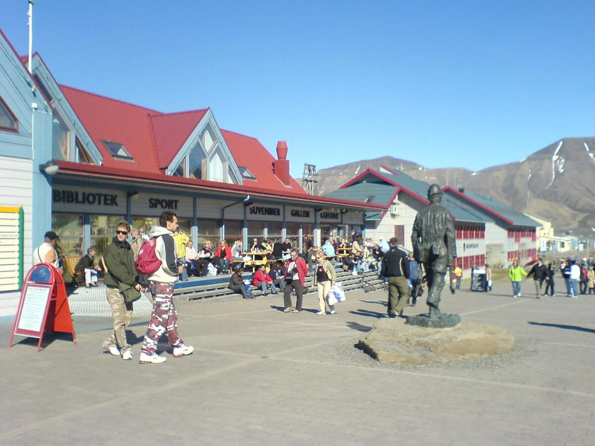 Ambiente animado en la calle principal de Longyearbyen, con turistas y locales frente a tiendas y cafeterías.