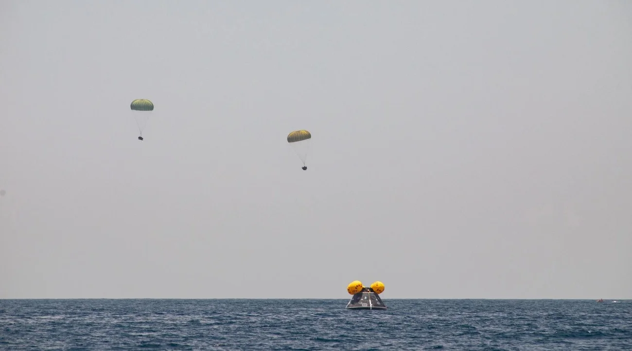 Cápsula espacial ameriza en el océano asistida por paracaídas amarillos, tras un ensayo de aborto de ascenso en Florida.