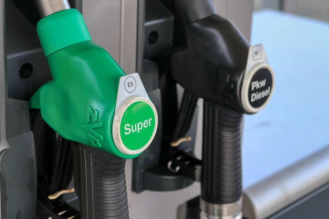 Dos pistolas de surtidor en estación de gasolina, una verde con la palabra Super