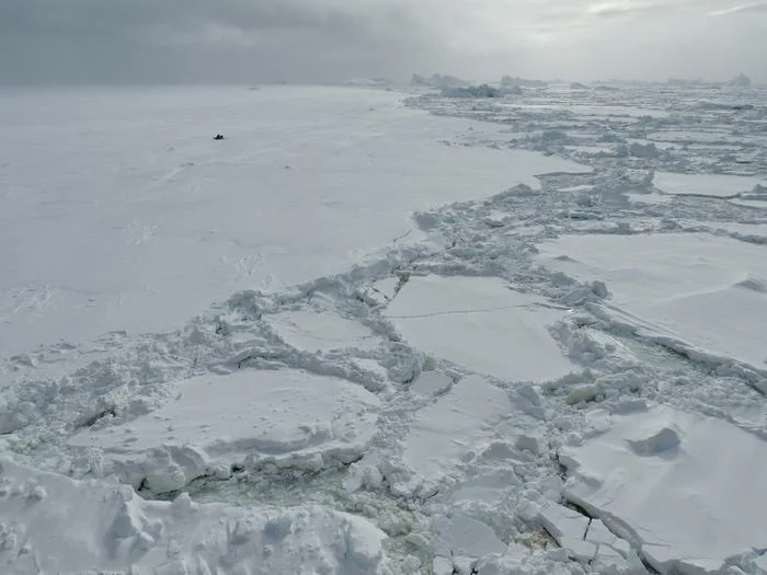 Superficie del hielo marino en el Océano Antártico, mostrando fracturas y placas irregulares flotando en el agua.