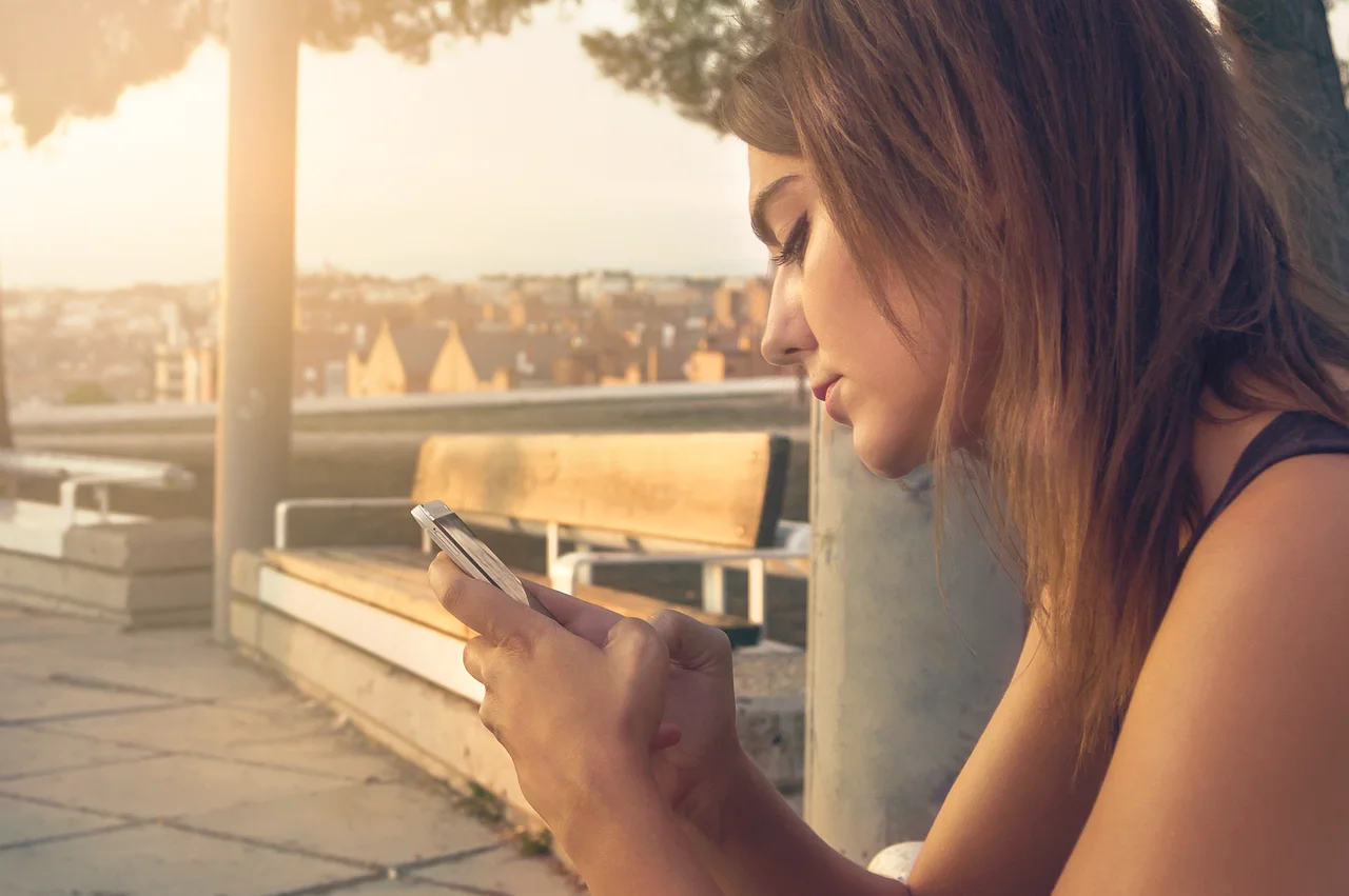 Joven sentada usando su teléfono móvil