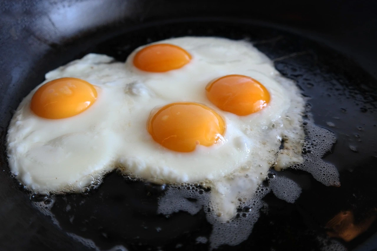 Huevos fritos cocinándose en una sartén con aceite caliente.