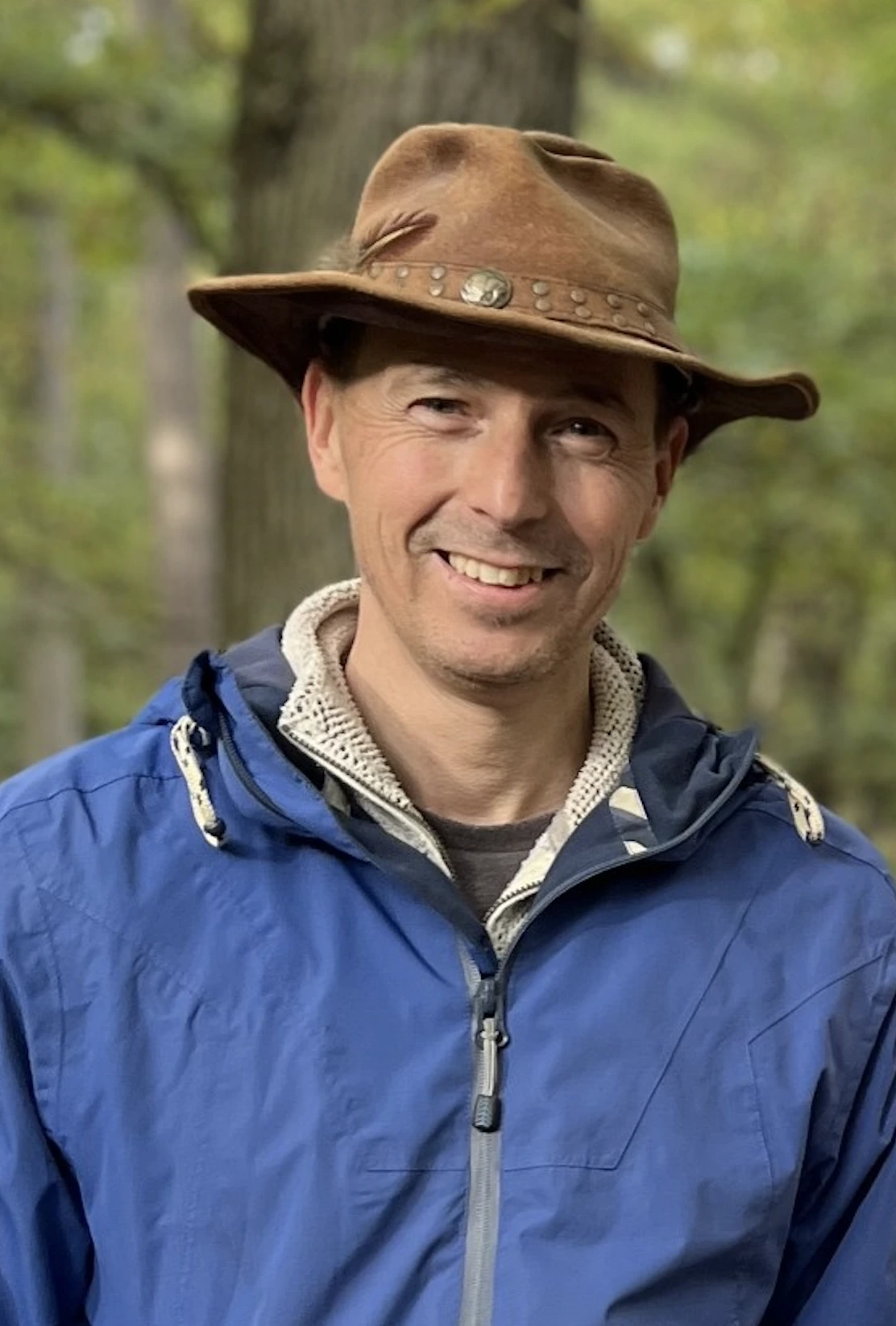 Profesor Cock van Oosterhout con sombrero marrón y chaqueta azul en un entorno natural