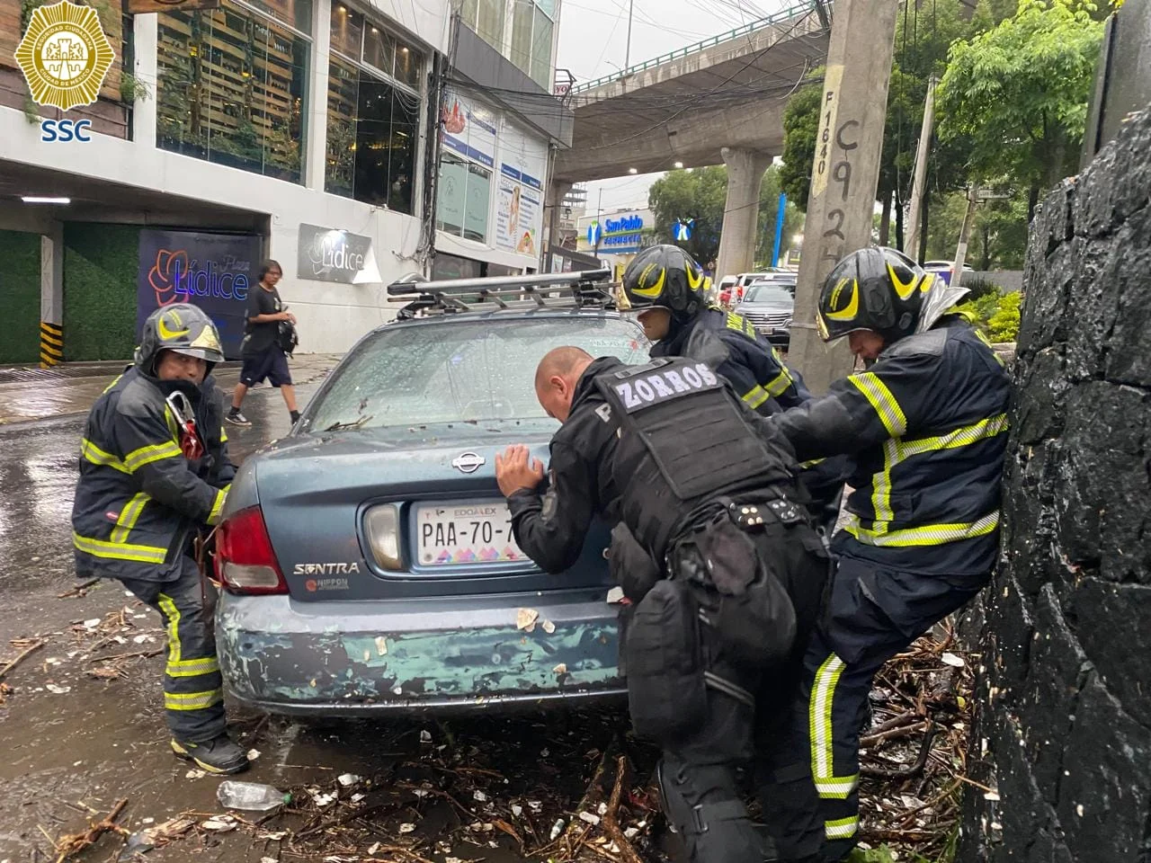Bomberos y policías de la SSC auxilian un vehículo atascado tras las inundaciones en CDMX