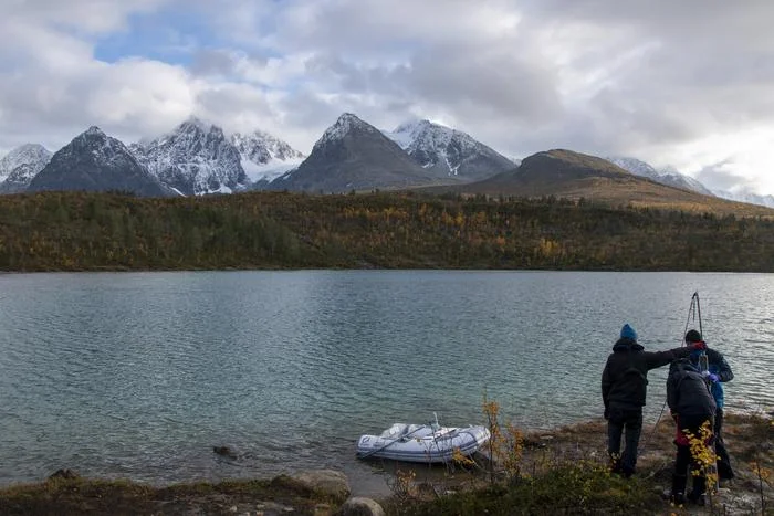 Investigadores sobre la superficie helada del lago Aspevatnet en Noruega, preparando equipos para extraer muestras de sedimentos