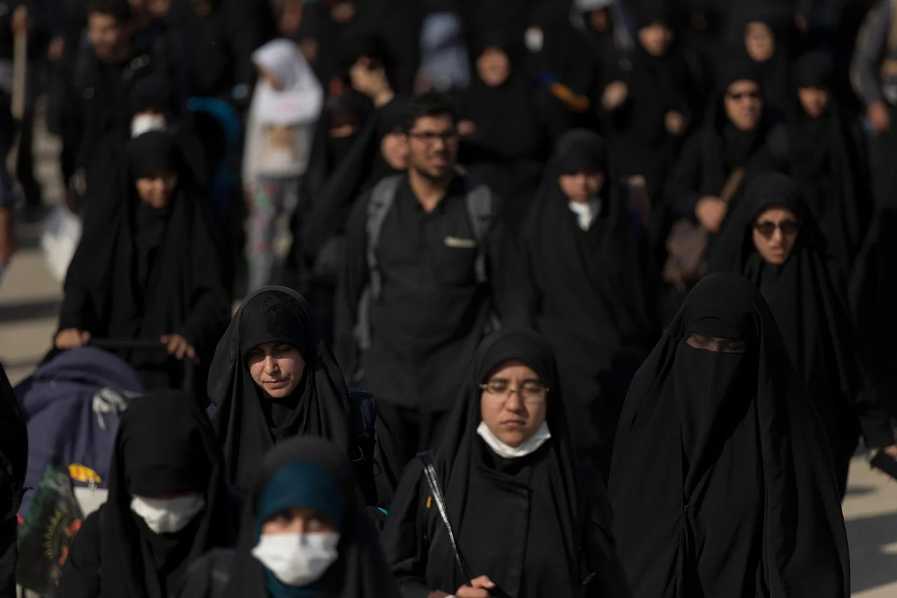 Grupo de inmigrantes con hiyab avanzan juntos por una vía pública