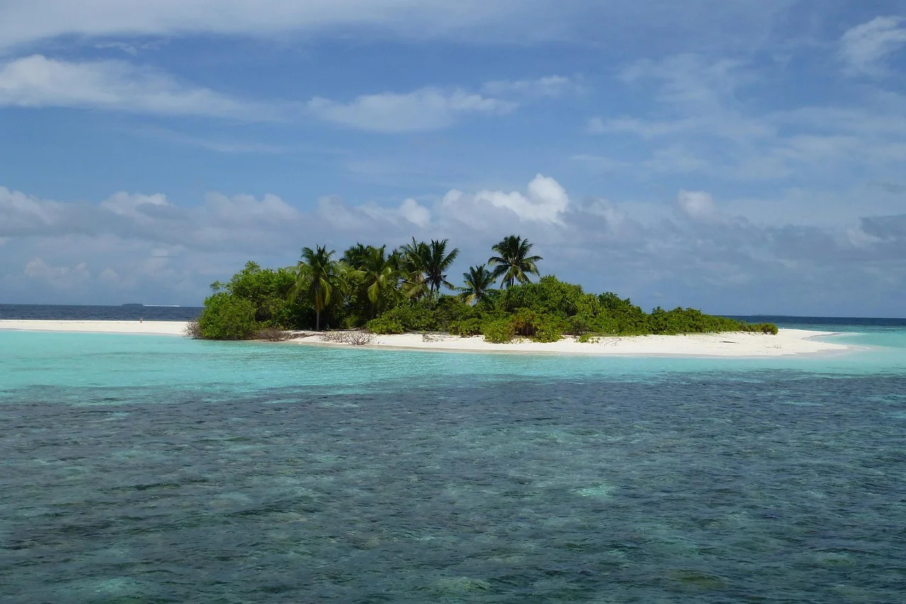 Isla coralina en Maldivas con arena blanca, palmeras y aguas turquesas