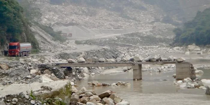 Puente destruido y escombros arrastrados por la inundación en el río Min tras un deslizamiento de tierra
