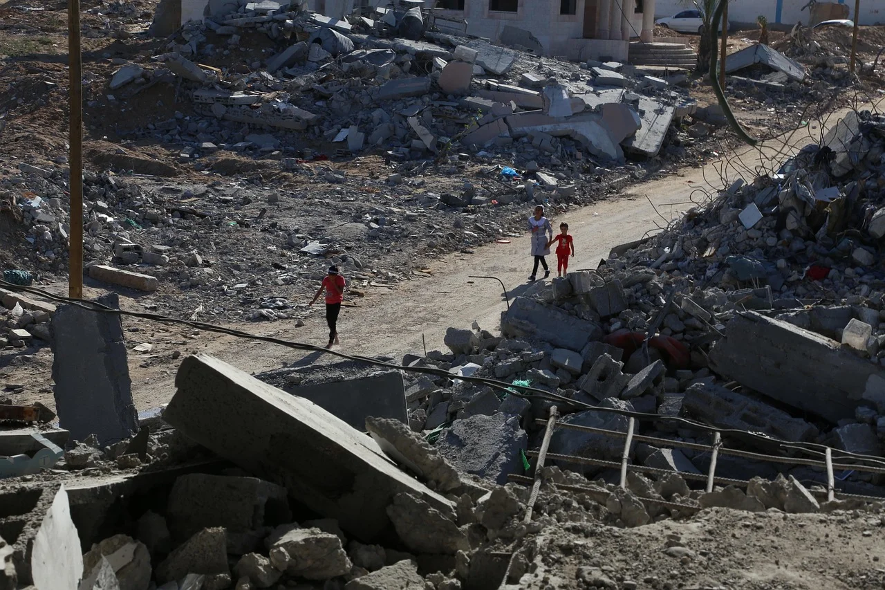 Personas caminando entre escombros en una zona devastada de Gaza
