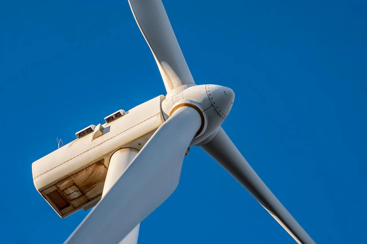 Primer plano de la góndola y las palas de una turbina eólica sobre cielo despejado
