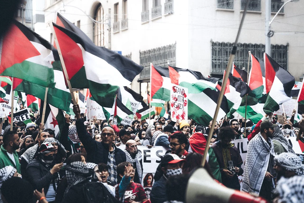 Manifestación con banderas palestinas y pancartas en una calle concurrida