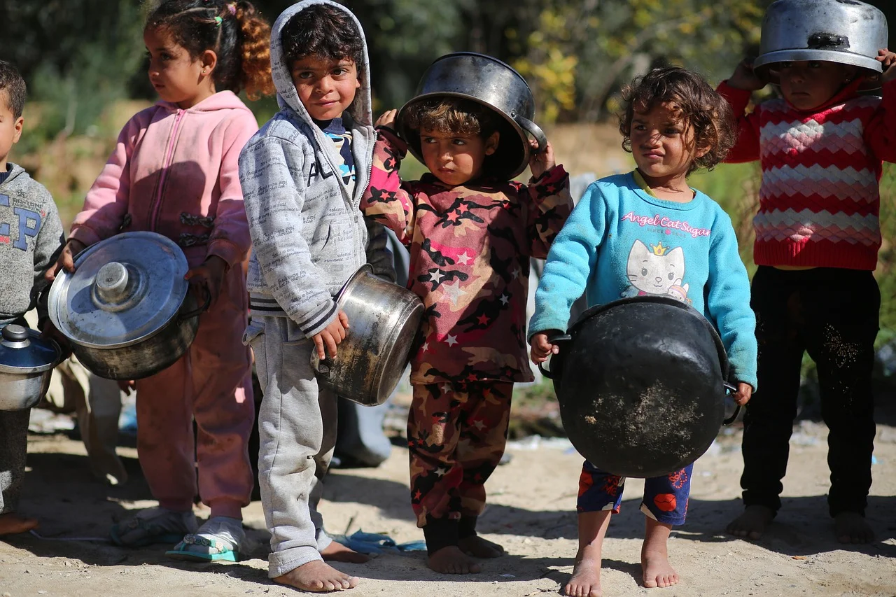 Niños en Gaza sosteniendo ollas vacías mientras esperan ayuda humanitaria