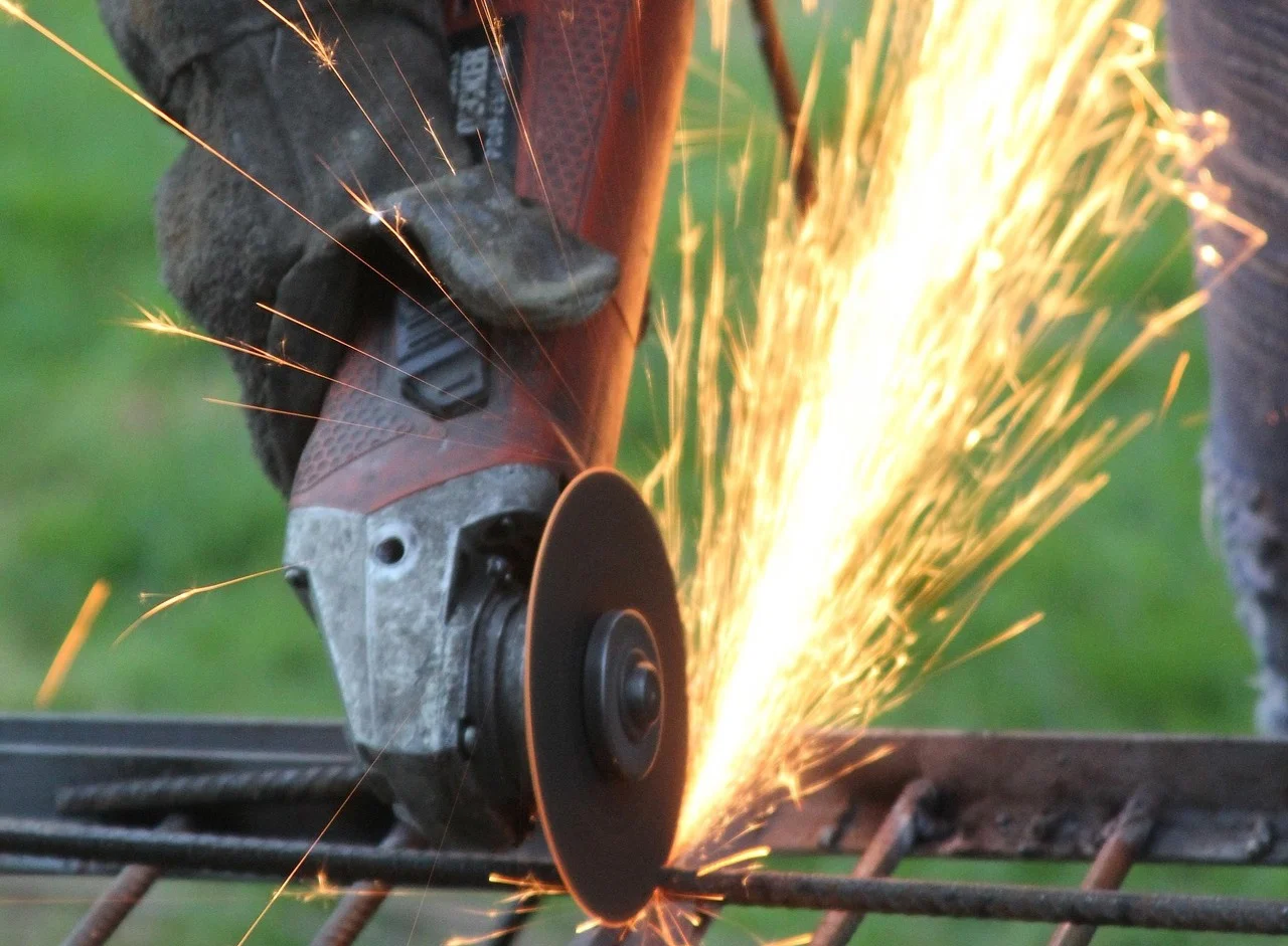 Trabajador utilizando una herramienta de corte que genera chispas sobre una barra metálica