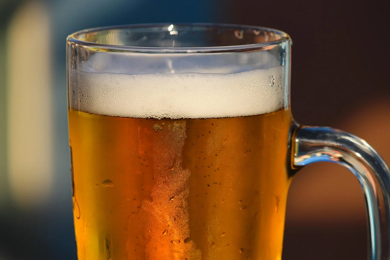 Vaso de cerveza dorada con espuma servido en un tarro de cristal