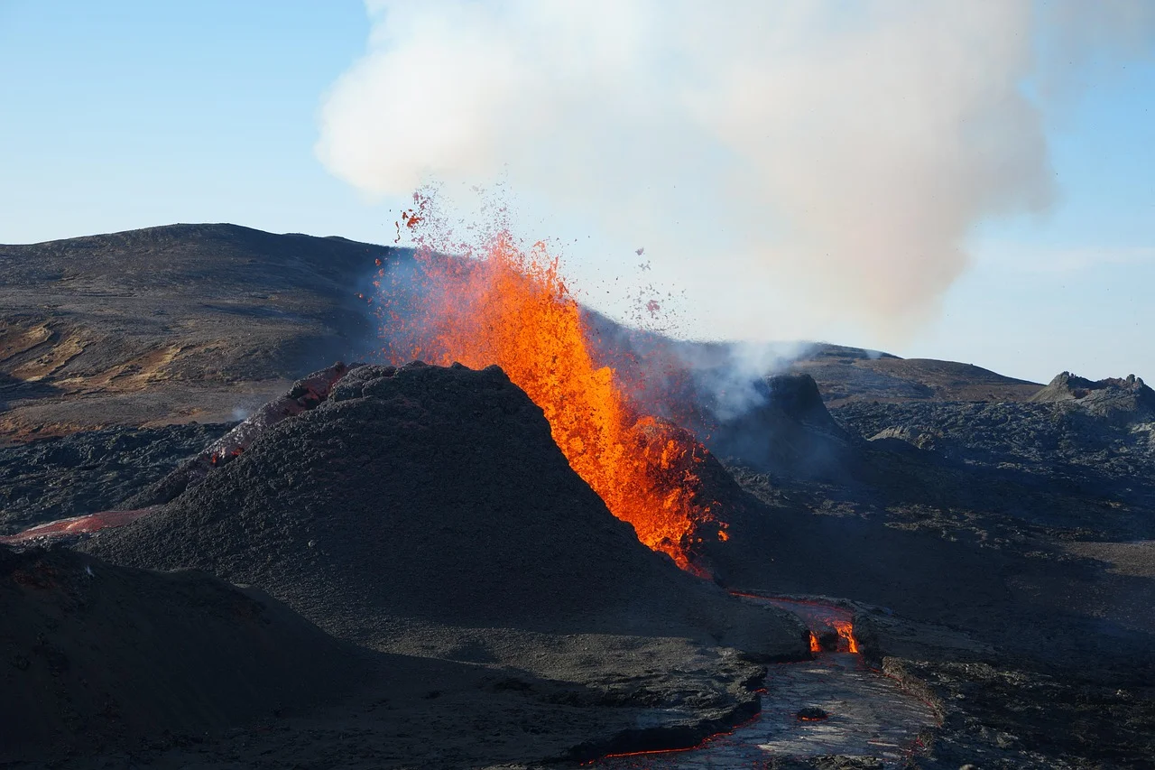 Erupción volcánica con lava incandescente y humo sobre un terreno oscuro