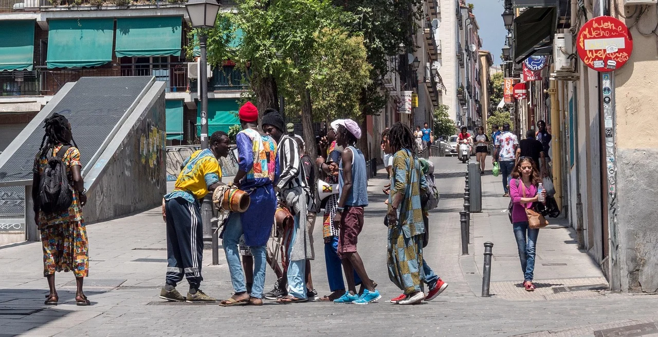 Grupo de inmigrantes en una calle concurrida de España, compartiendo un momento de conversación en un entorno urbano.