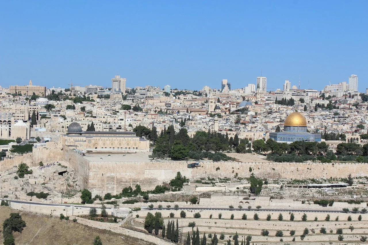 Vista panorámica de Jerusalén con la Cúpula de la Roca en primer plano y edificios modernos al fondo bajo un cielo despejado