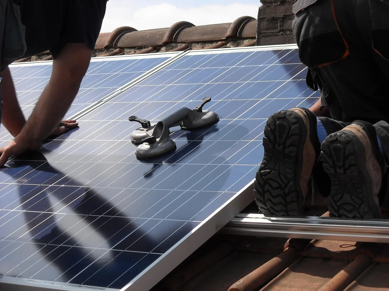 Técnicos fijando paneles solares en un tejado con herramientas especializadas durante el proceso de instalación