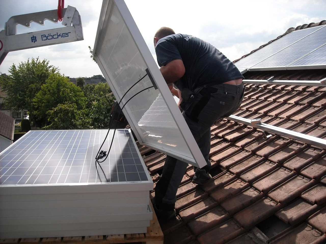 Trabajador instalando paneles solares en el tejado de una vivienda con estructura metálica de soporte