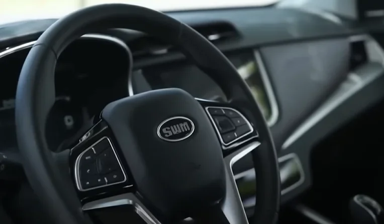 Volante y panel de control del interior de un automóvil SWM, con diseño moderno y mandos integrados en el volante