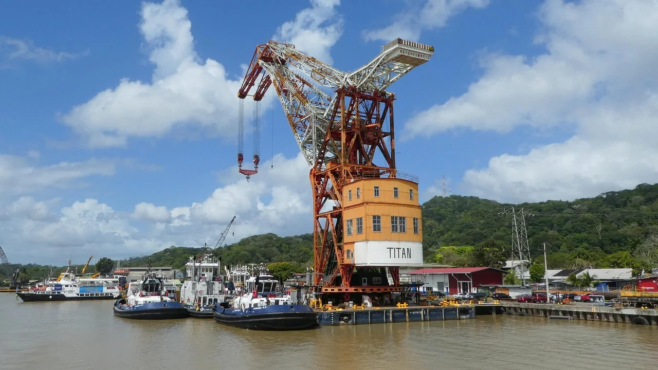 Vista del Canal de Panamá con grúas, embarcaciones y una estructura industrial de gran tamaño junto al puerto