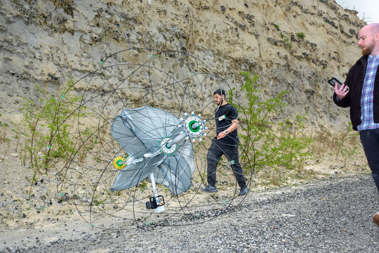 Investigadores caminando junto al prototipo científico Tumbleweed durante pruebas de campo en una cantera