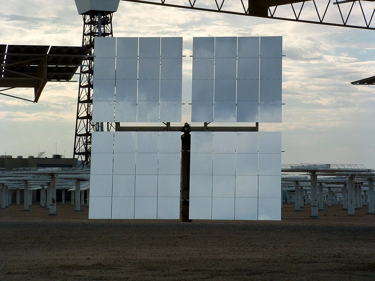 Heliostato de gran tamaño en una central termosolar de torre, orientado para reflejar la luz solar hacia el receptor central en lo alto de la torre principal