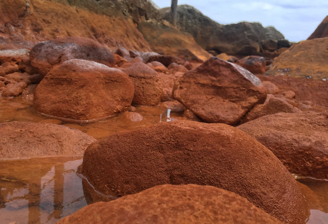 Detalle de sedimentos y rocas con precipitados de óxido de hierro en una fuente termal